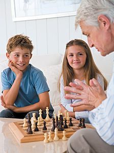 senior and kids playing chess